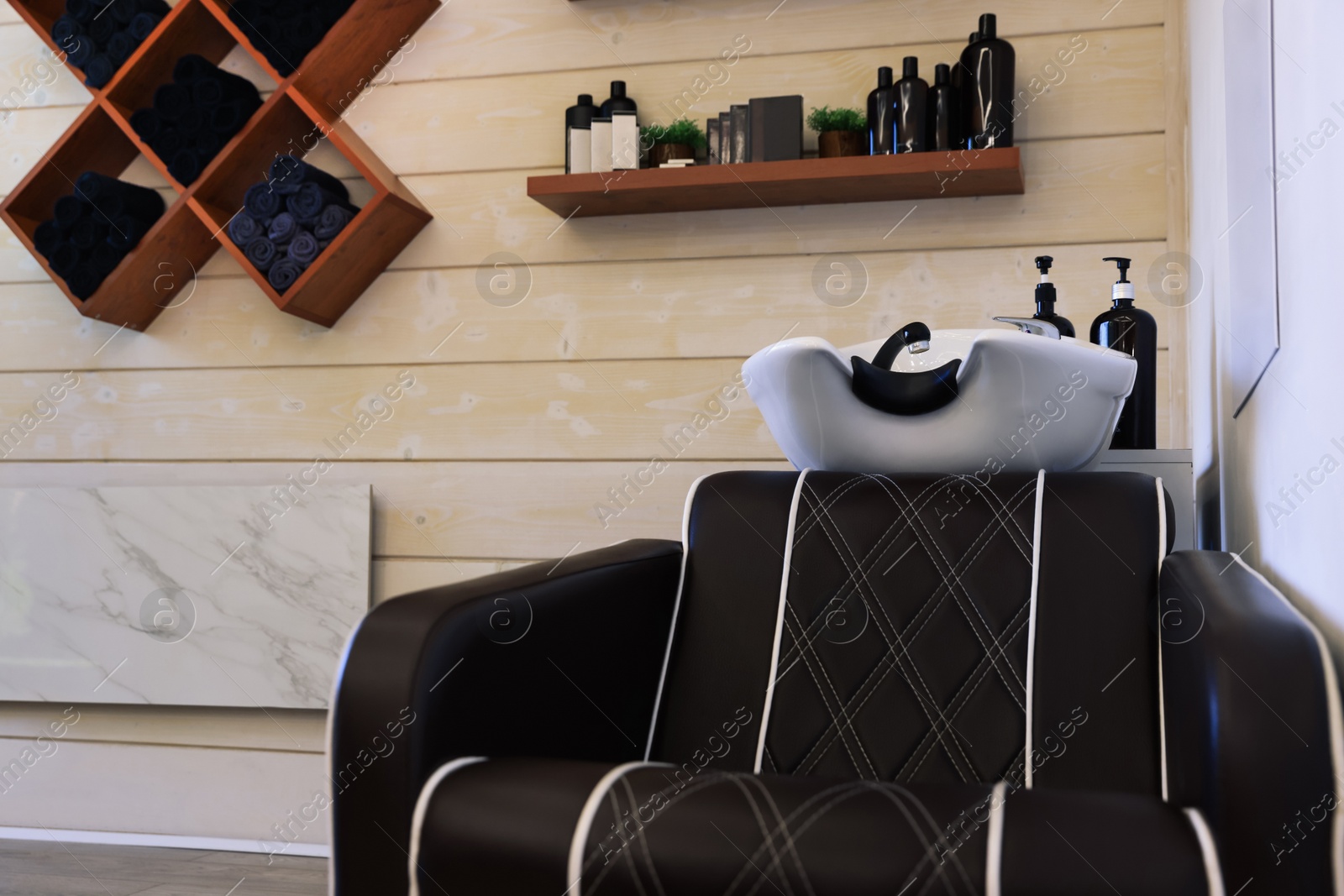 Photo of Modern wash unit with towels and professional care products in barbershop