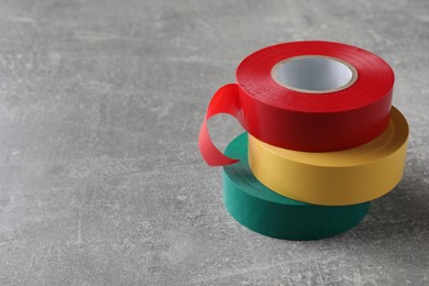 Photo of Colorful insulating tapes on light grey table. Space for text