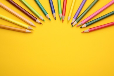 Colorful wooden pencils on yellow background, flat lay. Space for text