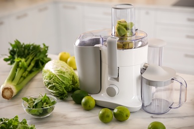 Photo of Modern juicer with fresh fruits on table in kitchen