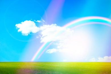 Image of Picturesque view of green meadow and beautiful rainbow in blue sky on sunny day