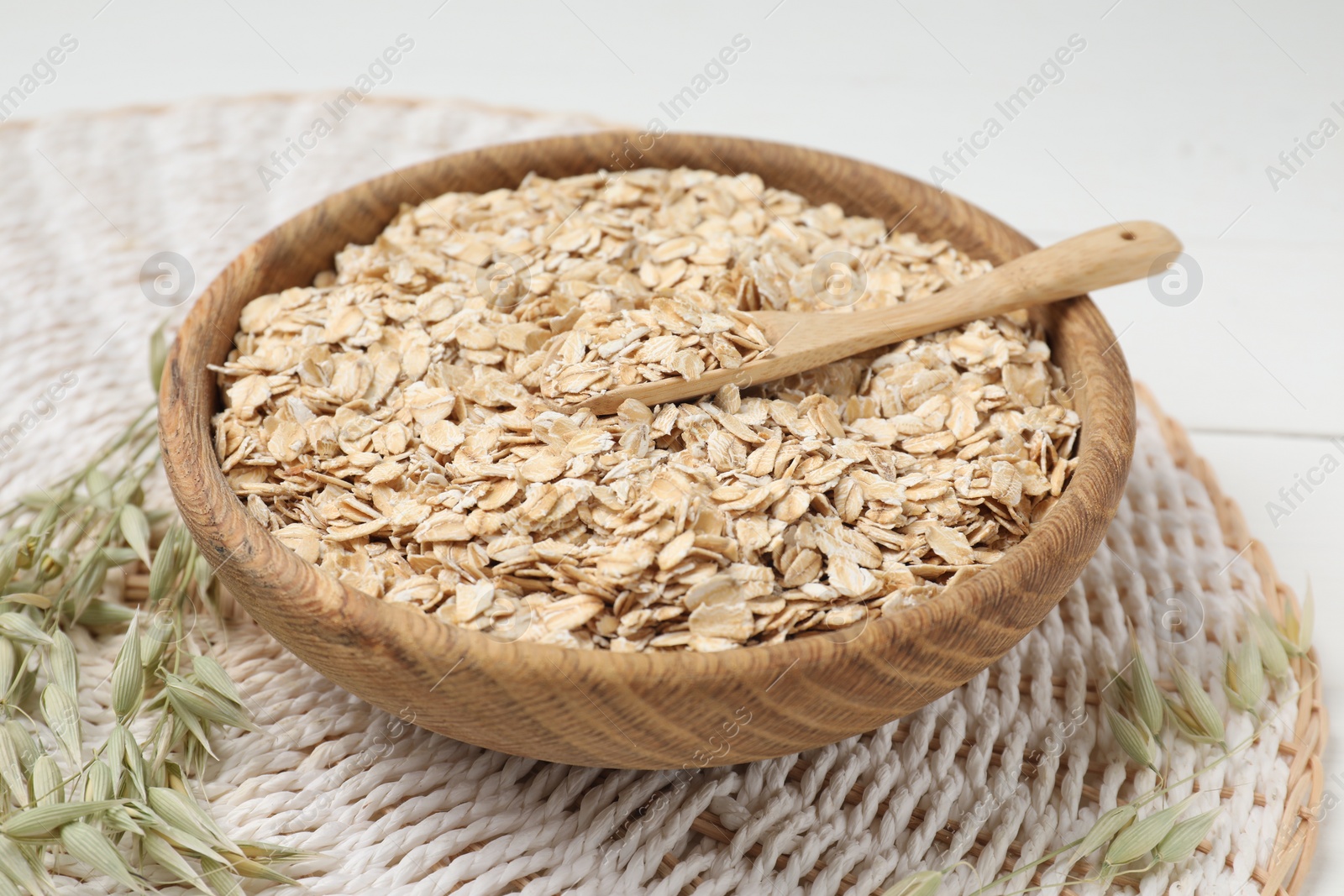 Photo of Bowl and spoon of oatmeal with florets on table, closeup