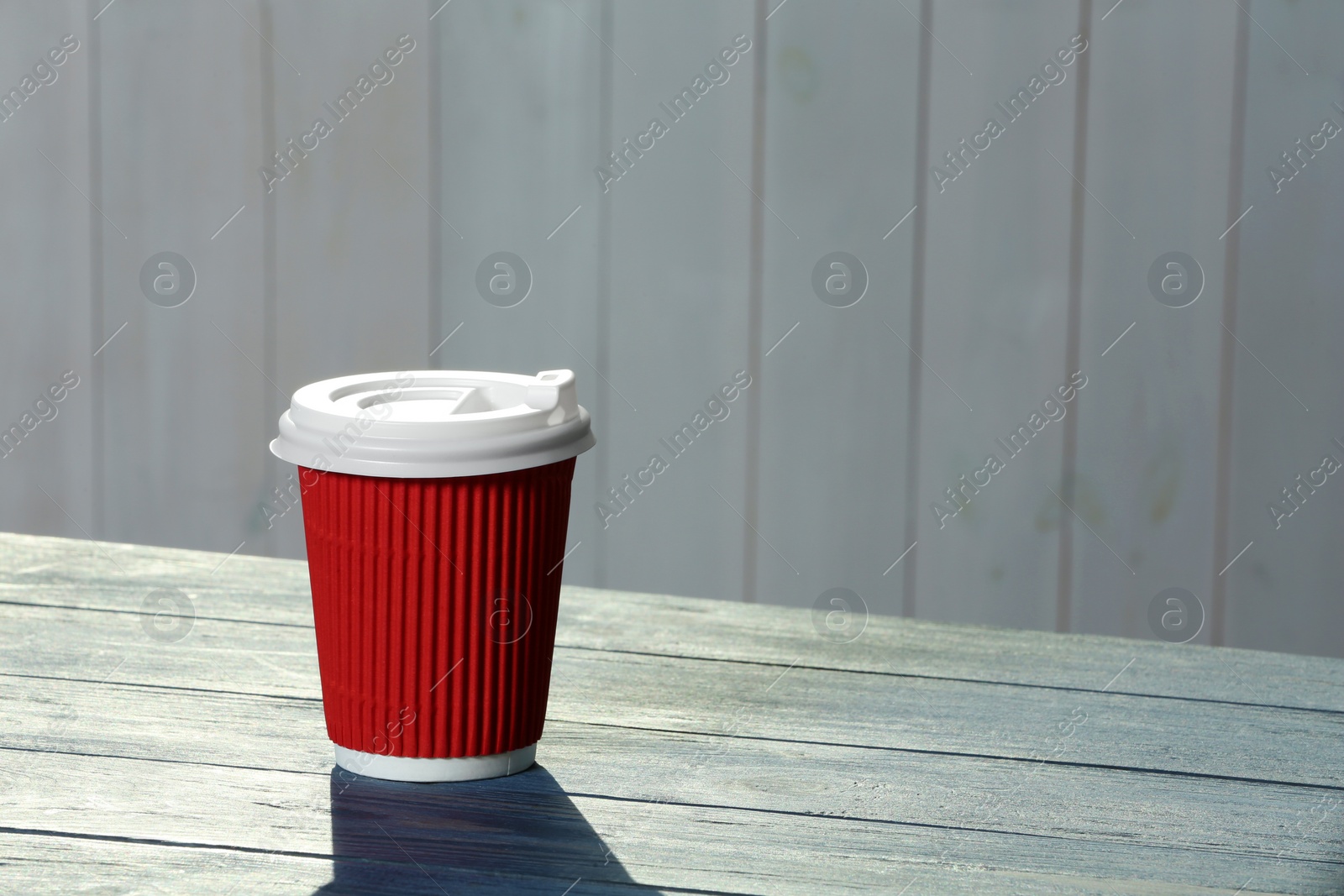Photo of Cardboard coffee cup with lid on wooden table. Space for text
