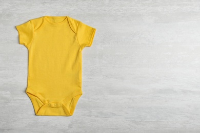 Baby bodysuit on wooden background, top view. Space for text