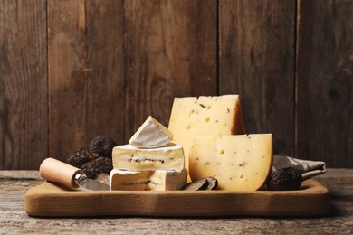 Different types of cheese and fresh truffles on wooden table