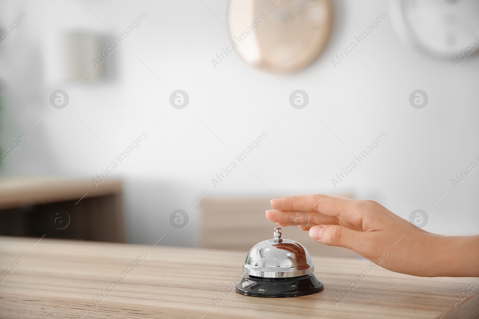 Photo of Woman ringing service bell on reception desk in hotel, closeup