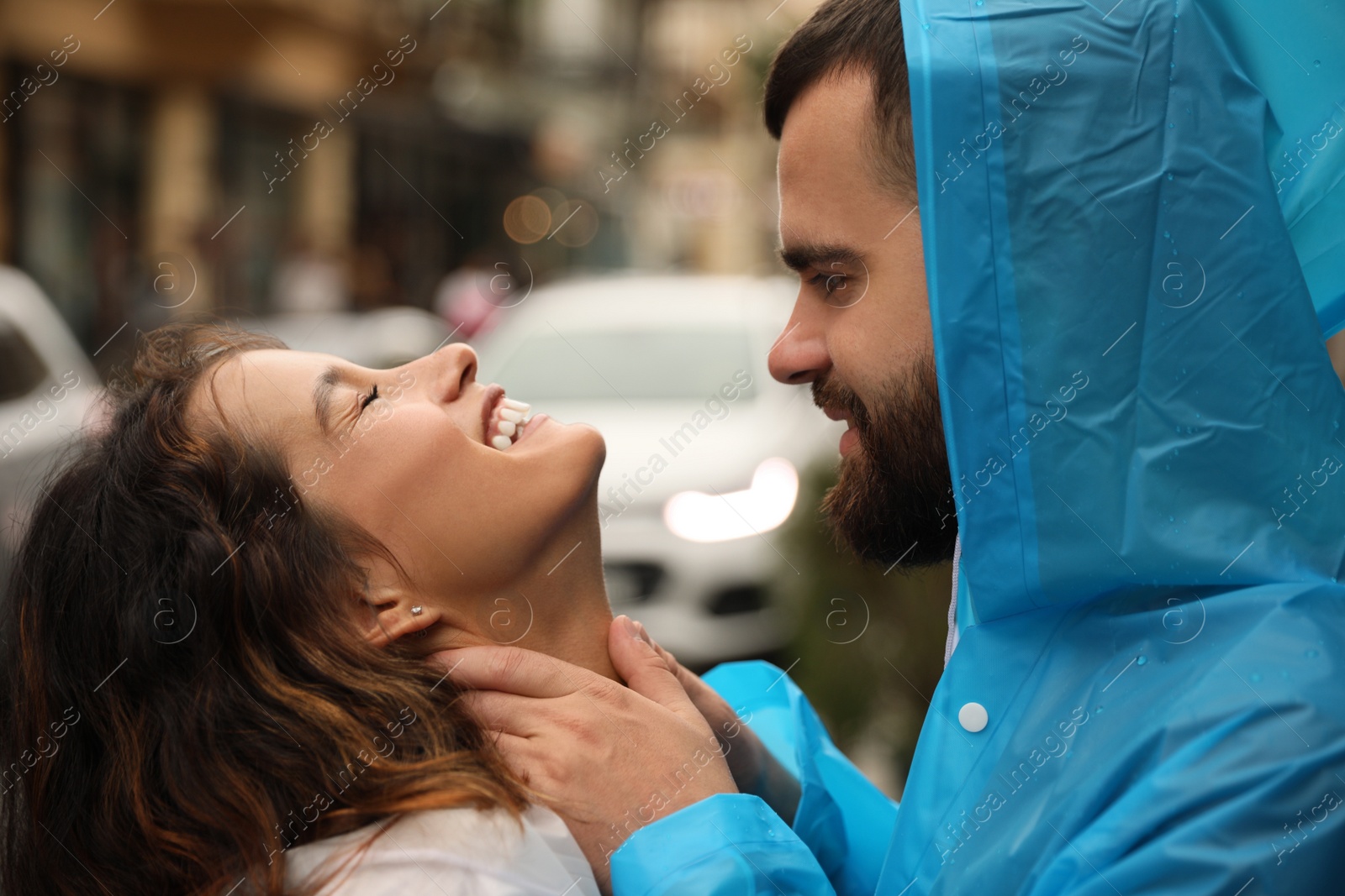 Photo of Young couple in raincoats enjoying time together on city street