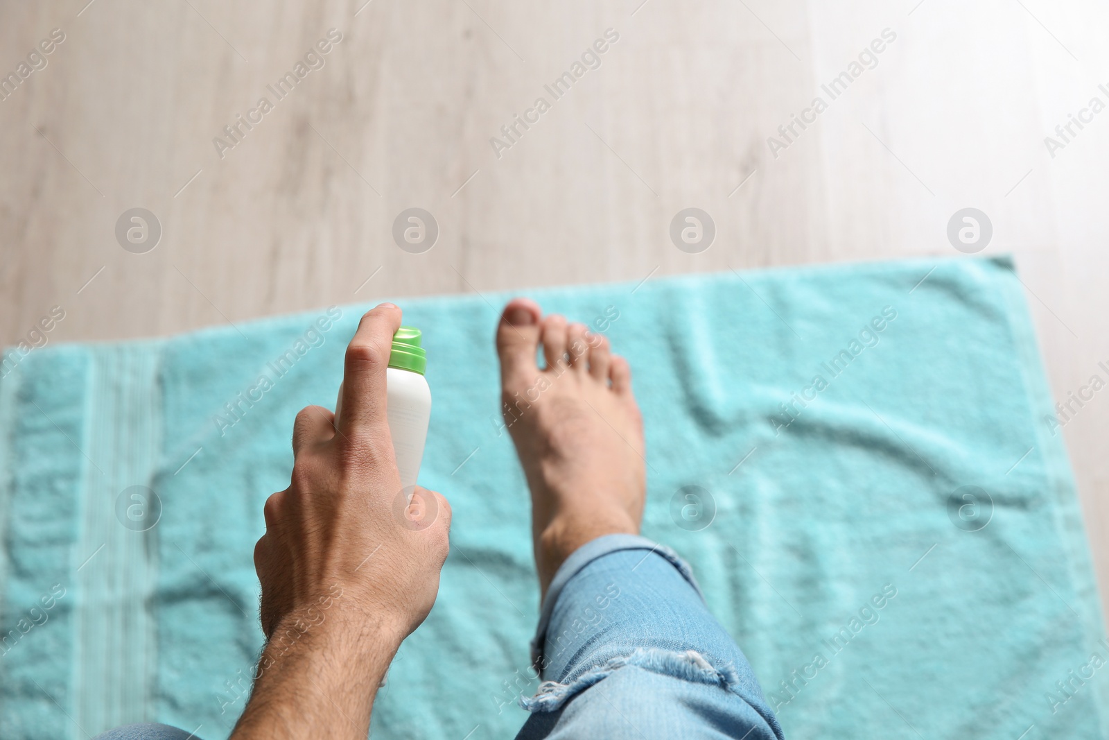 Photo of Young man using deodorant for feet at home, closeup