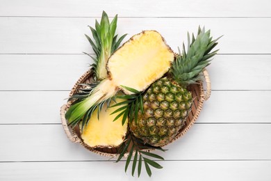Whole and cut ripe pineapples on white wooden table, top view