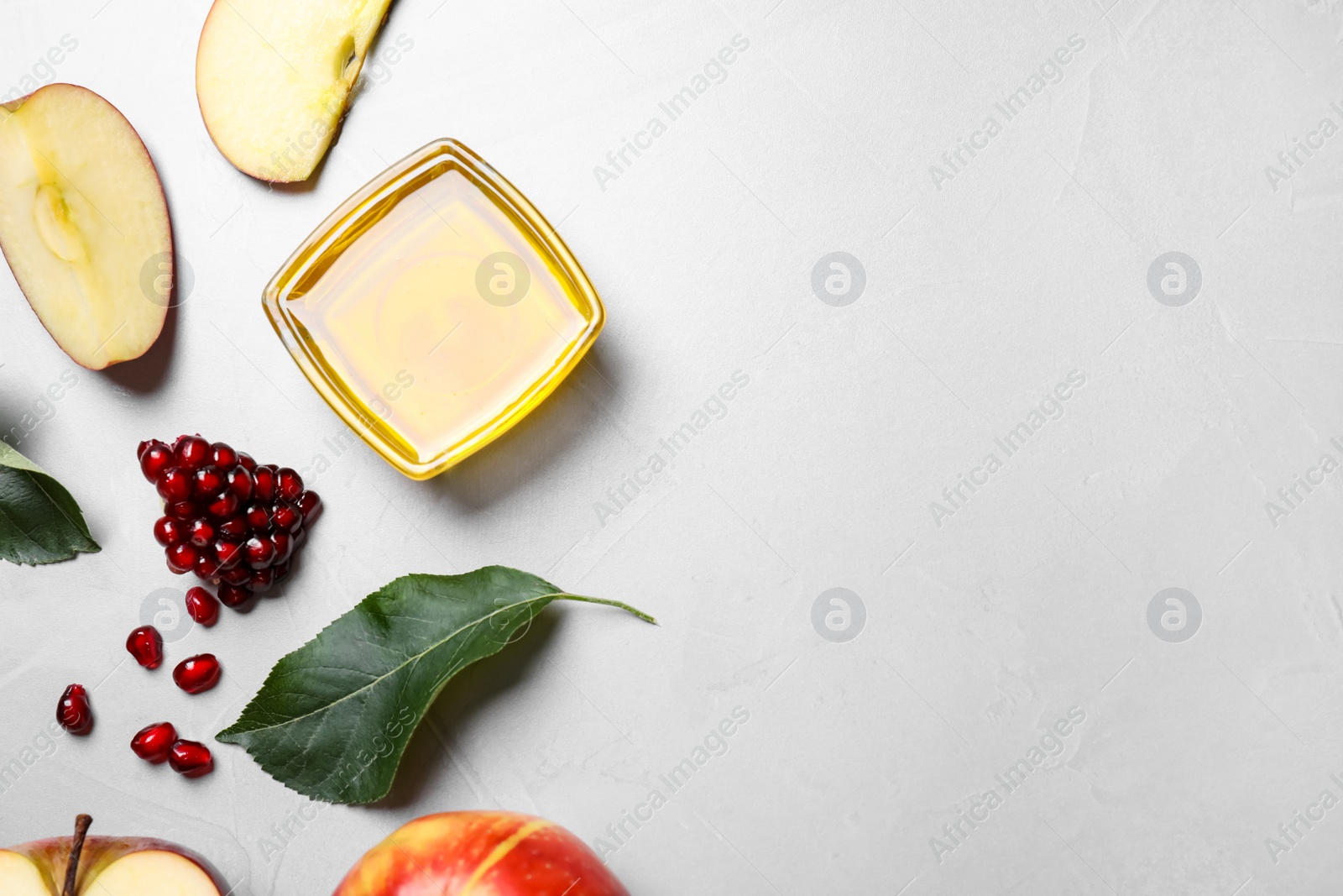 Photo of Honey, apples and pomegranate on light table, flat lay with space for text. Rosh Hashanah holiday