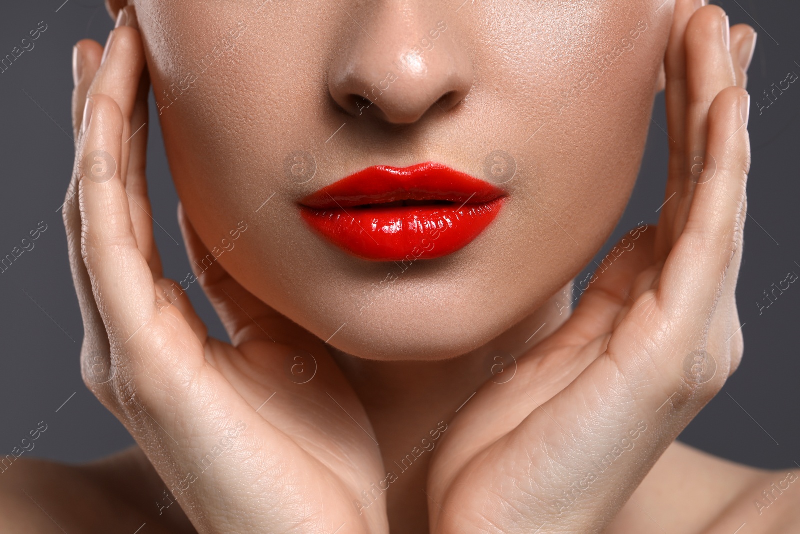 Photo of Young woman with beautiful red lips on grey background, closeup