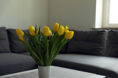 Photo of Bouquet of beautiful yellow tulips on table in living room, space for text