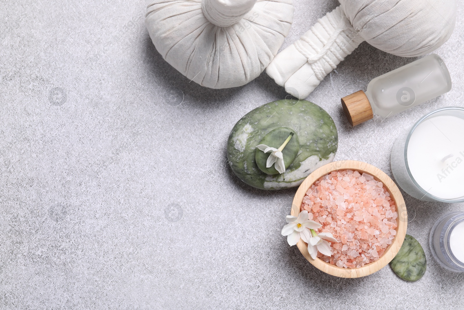 Photo of Flat lay composition with herbal massage bags, spa products and flowers on light grey table. Space for text