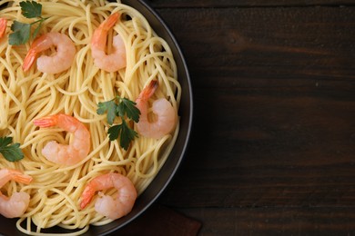 Photo of Tasty spaghetti with shrimps and parsley in bowl on wooden table, top view. Space for text