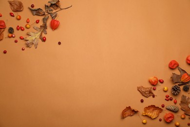 Photo of Dry autumn leaves, berries and cones on light brown background, flat lay. Space for text
