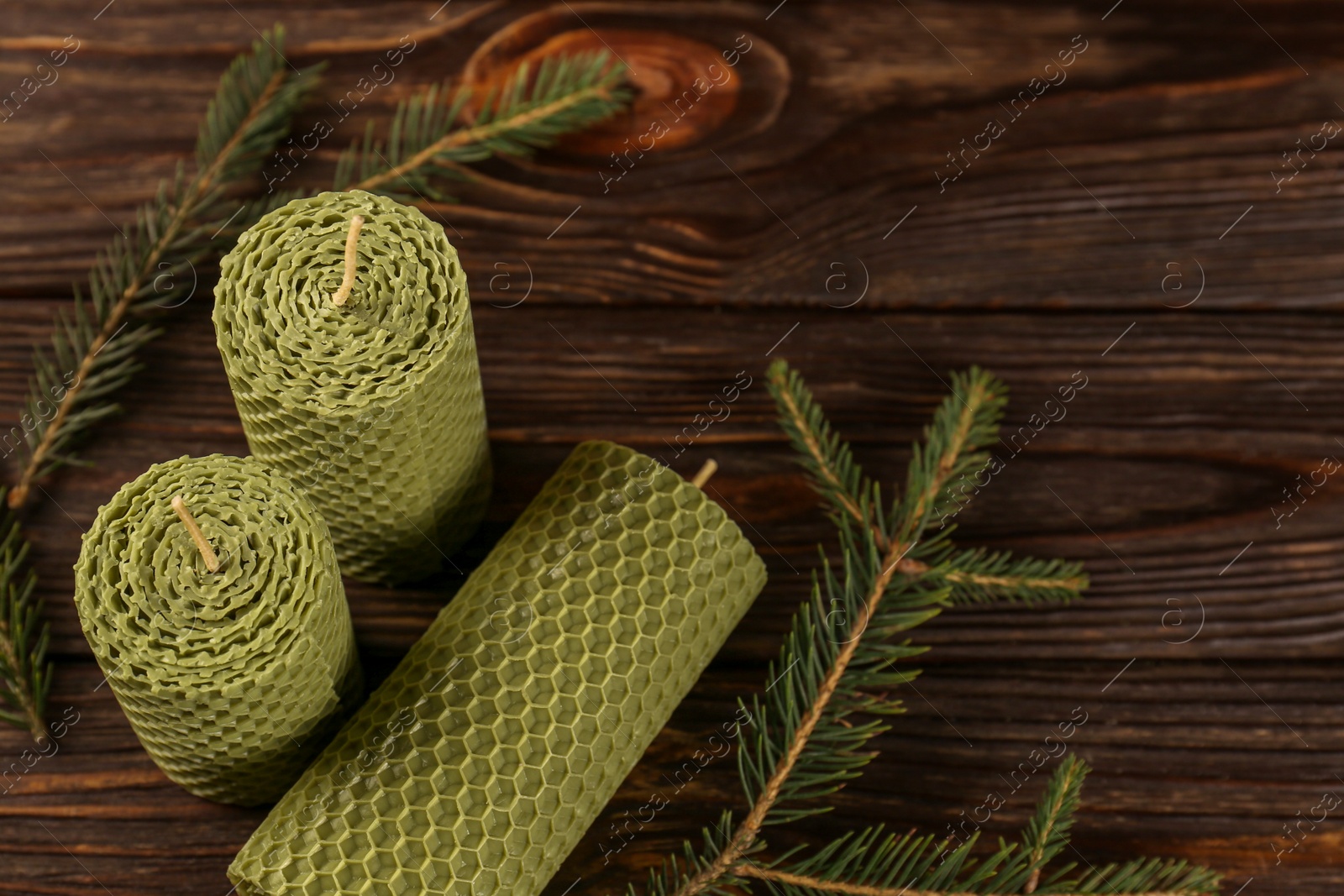 Photo of Stylish elegant beeswax candles with spruce branches on wooden table, above view