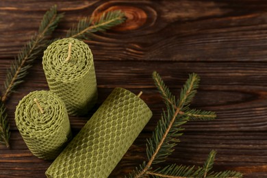 Stylish elegant beeswax candles with spruce branches on wooden table, above view