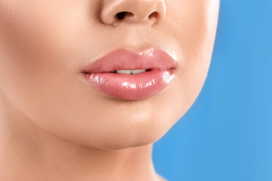 Photo of Young woman with beautiful full lips on light blue background, closeup