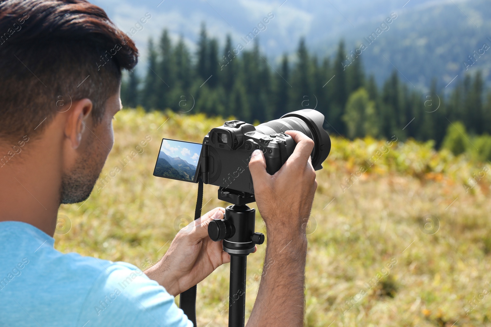 Photo of Man taking photo of nature with modern camera on stand outdoors