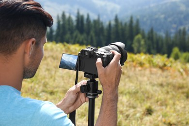 Man taking photo of nature with modern camera on stand outdoors