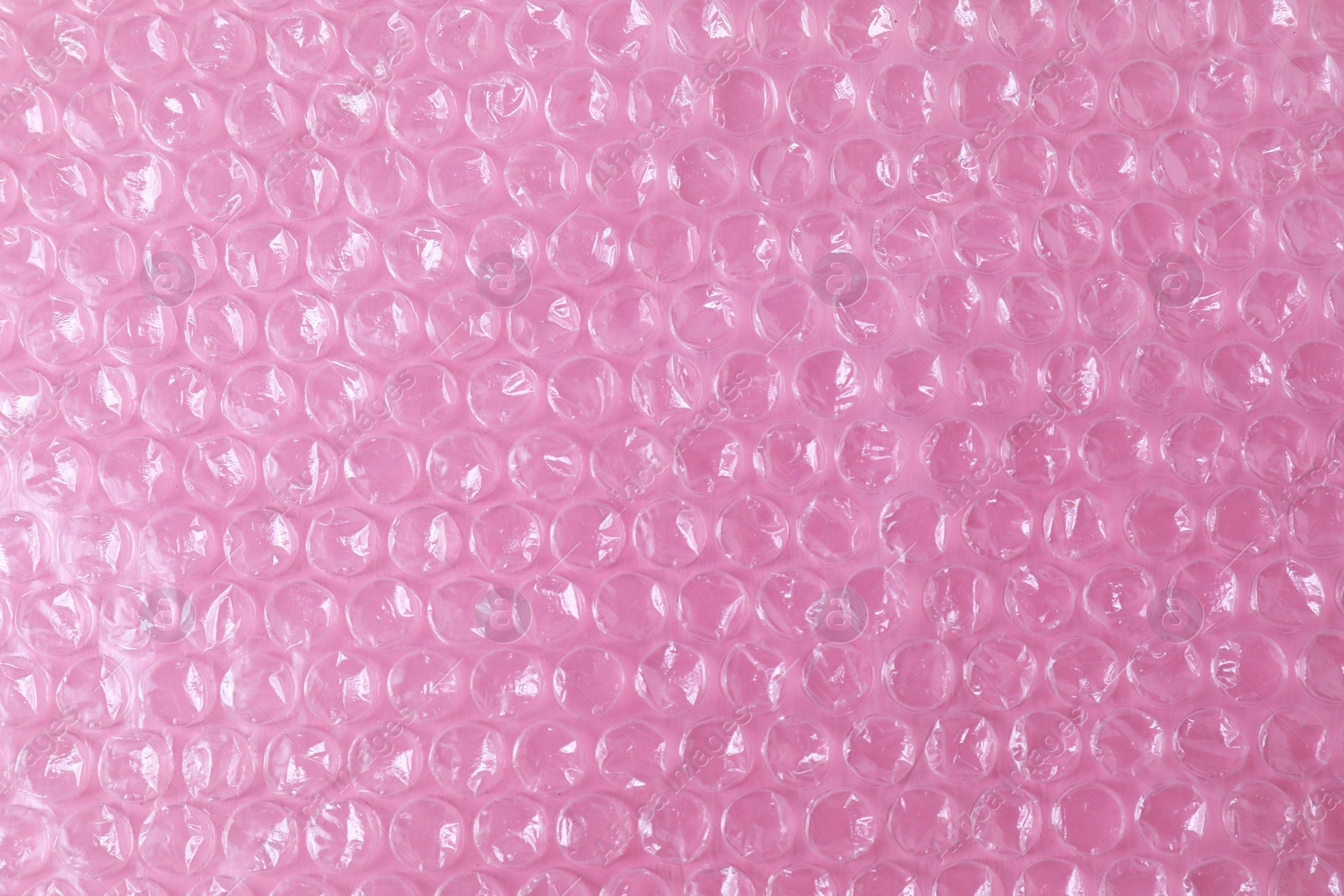 Photo of Transparent bubble wrap on pink background, top view