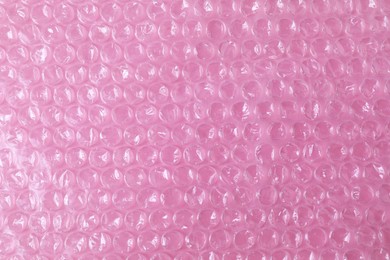 Photo of Transparent bubble wrap on pink background, top view