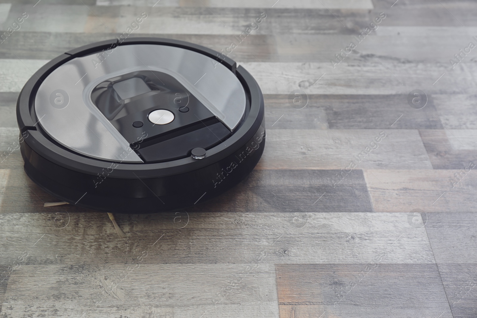 Photo of Modern robotic vacuum cleaner on wooden floor. Space for text
