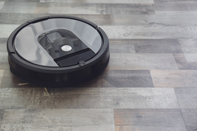 Modern robotic vacuum cleaner on wooden floor. Space for text