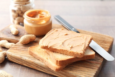 Tasty toasts with peanut butter on wooden board