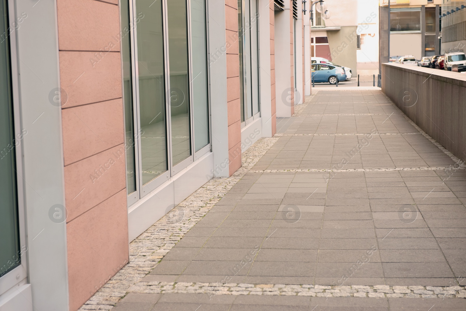 Photo of Tiled pavement near building outdoors. Sidewalk covering