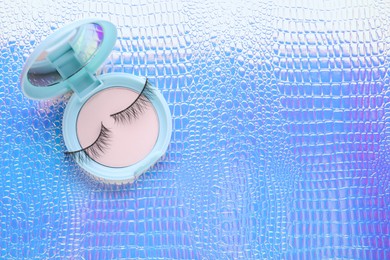 Photo of False eyelashes and cosmetic product on texture colorful background, top view. Space for text