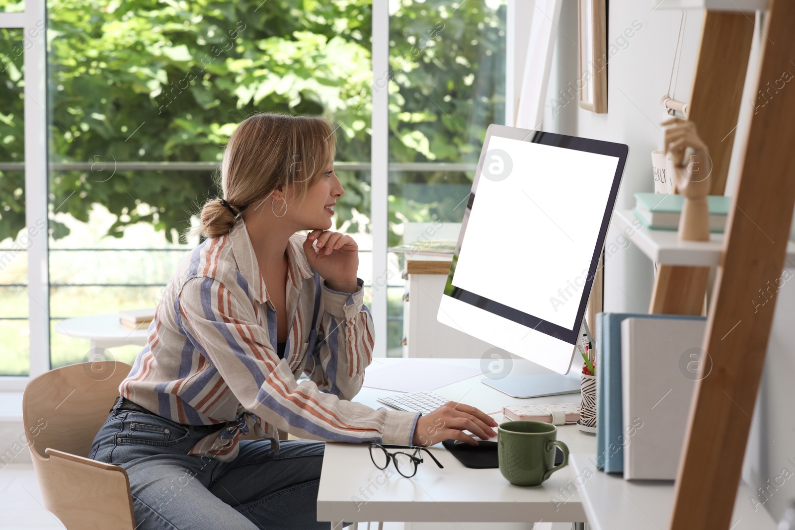 Photo of Young woman working on computer at table in room