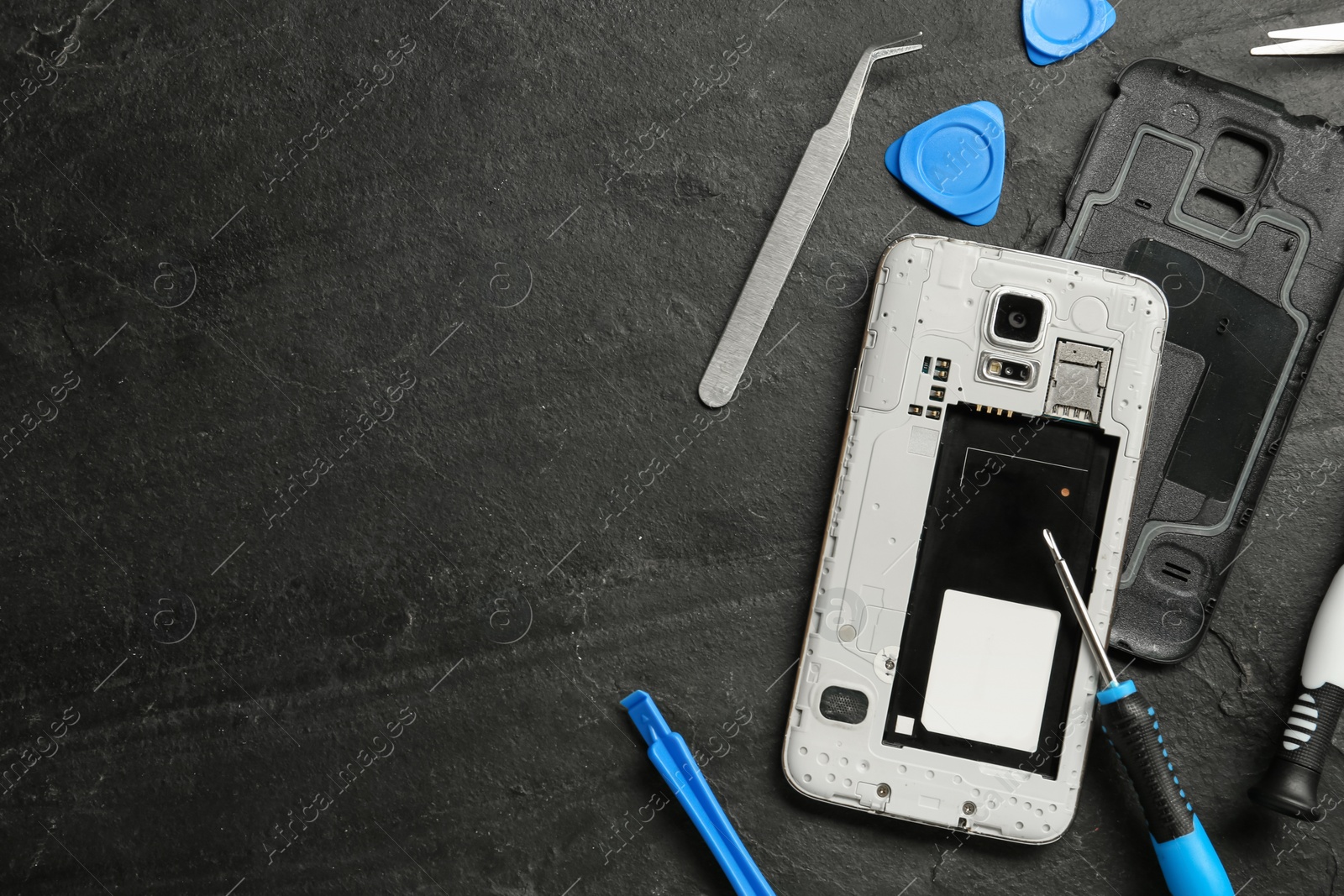 Photo of Damaged smartphone and repair tools on black background, flat lay. Space for text