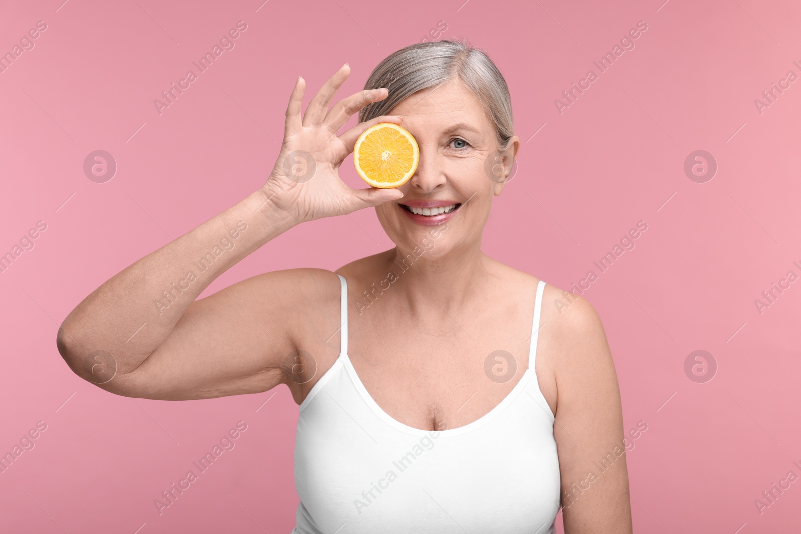 Photo of Beautiful woman with half of orange rich in vitamin C on pink background