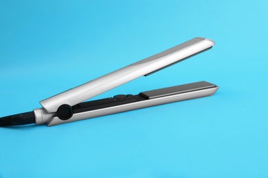 Photo of Modern hair iron for straightening on color background