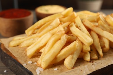 Photo of Delicious french fries on board, closeup view