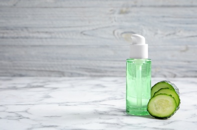Photo of Fresh cut cucumber and tonic in bottle on table against light background. Space for text