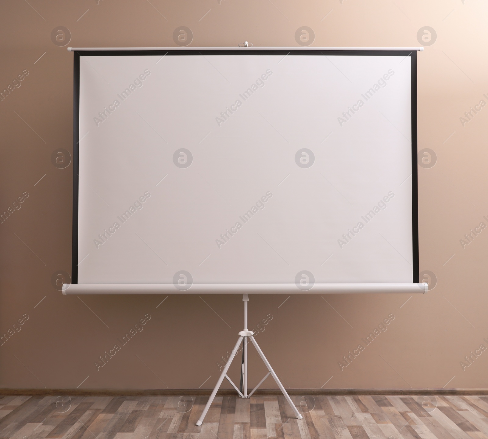 Photo of Blank projection screen near beige wall indoors. Space for design