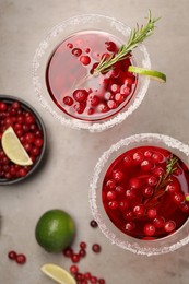 Tasty cranberry cocktail with rosemary and lime in glasses on grey table, flat lay