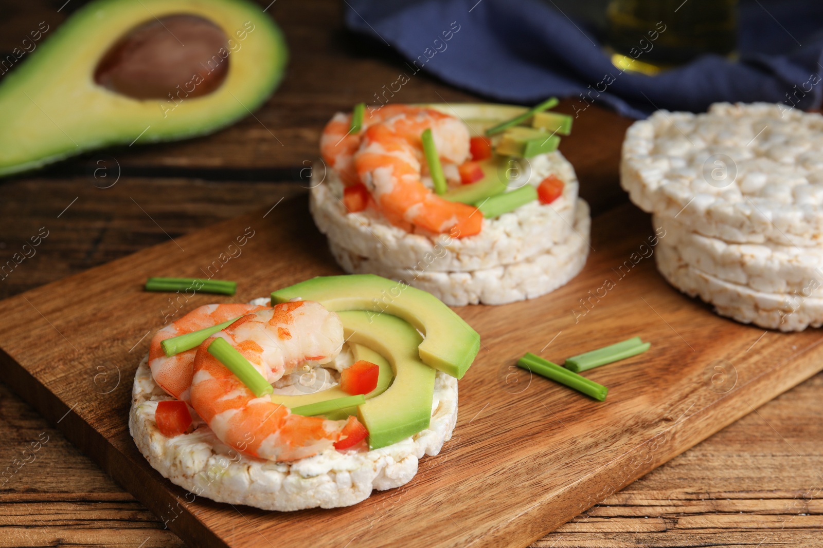 Photo of Puffed rice cakes with shrimps and avocado on wooden table