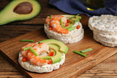 Photo of Puffed rice cakes with shrimps and avocado on wooden table