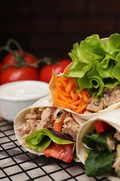 Photo of Delicious tortilla wraps with tuna on grill grate, closeup. Space for text