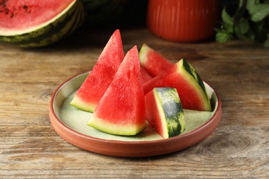 Photo of Plate with slices of juicy watermelon on wooden table