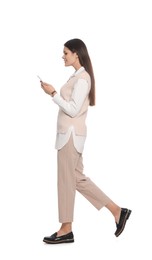 Young woman with smartphone walking on white background