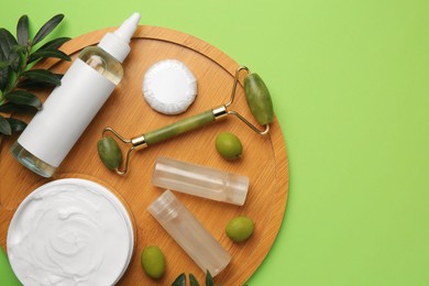 Photo of Different cosmetic products, face roller and olives on light green background, flat lay. Space for text