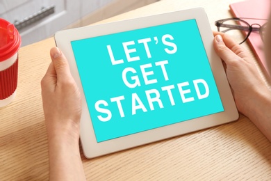 Image of Woman using tablet with phrase Let's Get Started at table, closeup