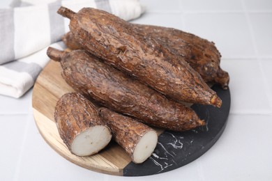 Photo of Whole and cut cassava roots on white tiled table