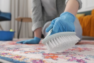 Photo of Woman cleaning carpet with brush indoors, closeup. Space for text