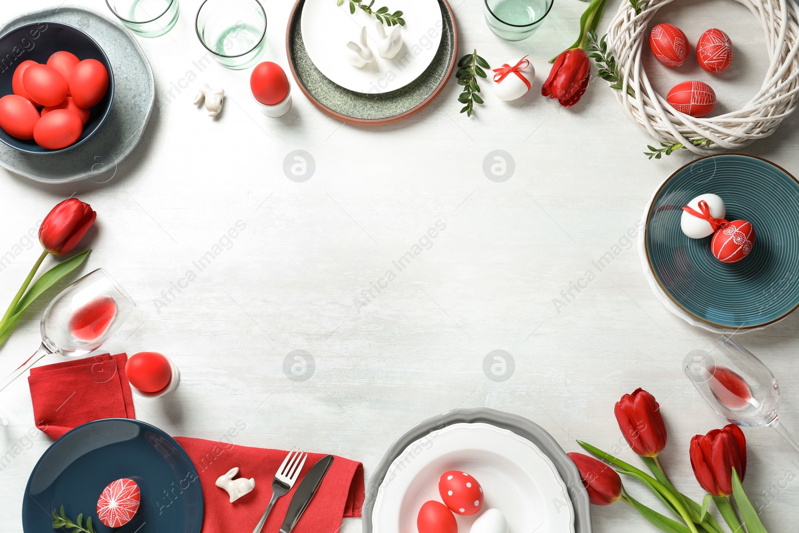 Photo of Festive Easter table setting with painted eggs on wooden background, top view. Space for text