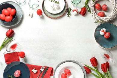 Festive Easter table setting with painted eggs on wooden background, top view. Space for text